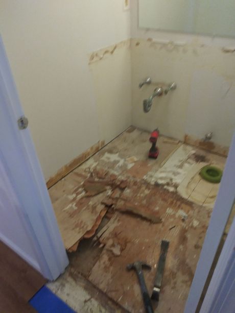A bathroom with a hammer and a drill on the floor.