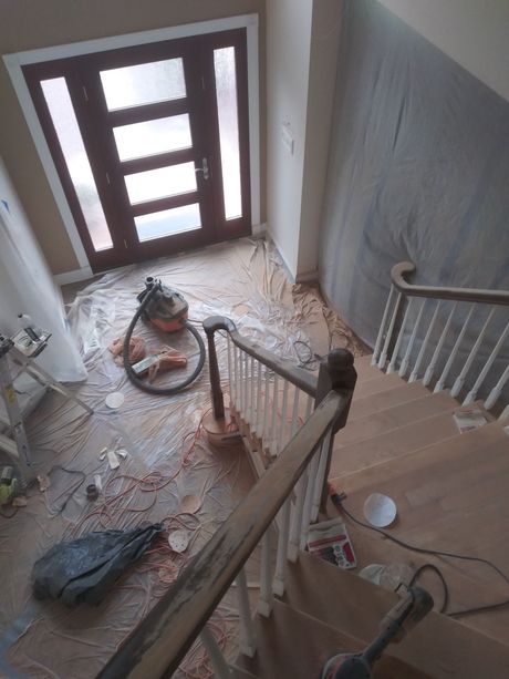 A vacuum cleaner is sitting on the floor next to a staircase.