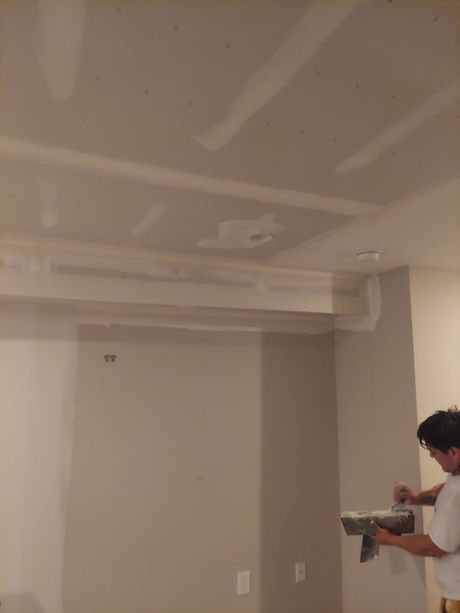 A man is working on a ceiling in a room.