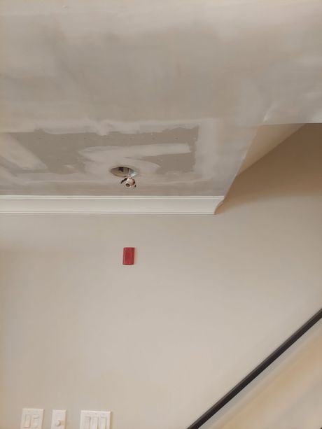 A room with a staircase and a ceiling that is being painted.