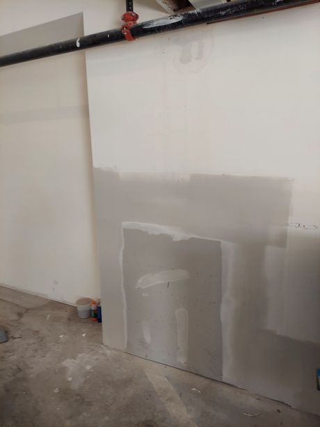 A white wall with a few pieces of drywall on it