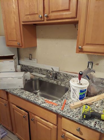 A kitchen counter with a sink and a bucket of super glue
