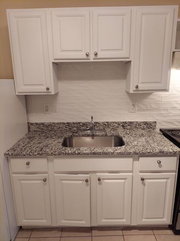 A kitchen with white cabinets , granite counter tops , and a sink.