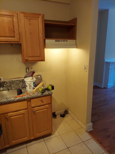 A kitchen with wooden cabinets , granite counter tops , a sink and a hood.