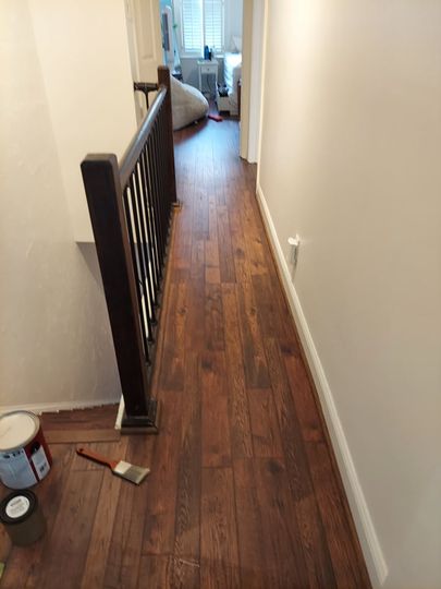 A hallway with hardwood floors and a black railing.