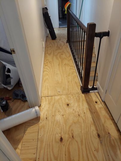 A hallway with a wooden floor and a metal railing.