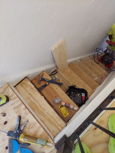 A wooden staircase is being built with tools on the floor.
