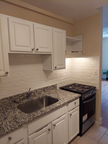 A kitchen with granite counter tops and white cabinets