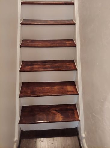 A staircase with wooden steps and white railing in a room.