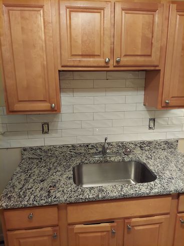 A kitchen with granite counter tops and a stainless steel sink