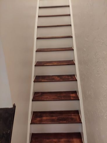 A staircase with wooden steps and white railing in a room.