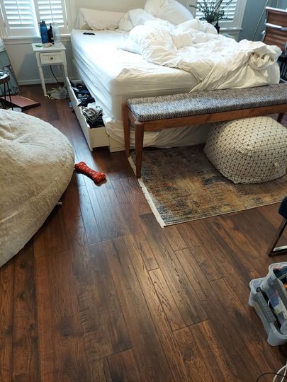 A bedroom with hardwood floors , a bed , a bench , and a bean bag chair.