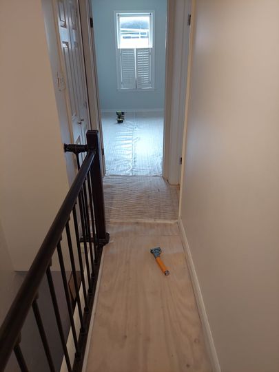 A hallway with a railing leading to a bedroom and a window.