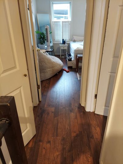 A hallway leading to a bedroom with hardwood floors and a bean bag chair.
