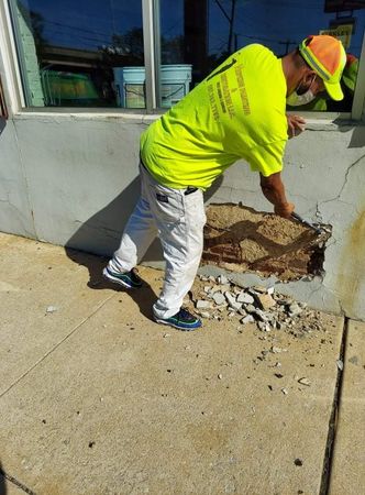 A man in a neon yellow shirt is working on a sidewalk.