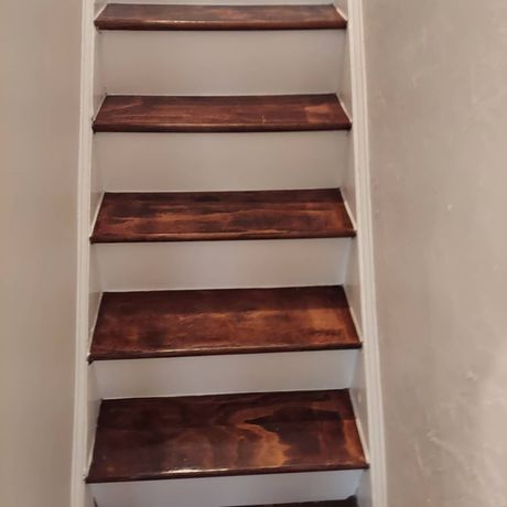 A set of wooden stairs with white steps in a room.