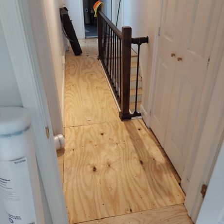 A hallway with a wooden floor and a metal railing