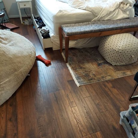A bedroom with hardwood floors , a bed , a bench , and a bean bag chair.
