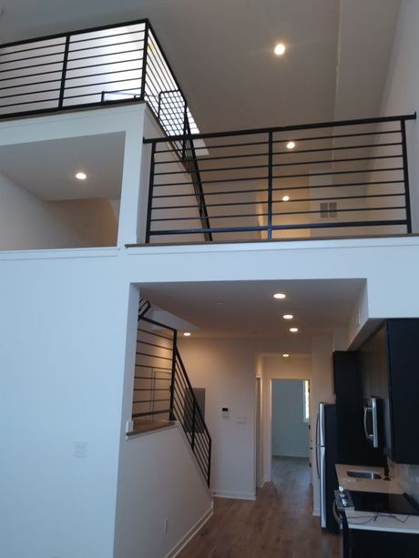 A room with a balcony and stairs in it