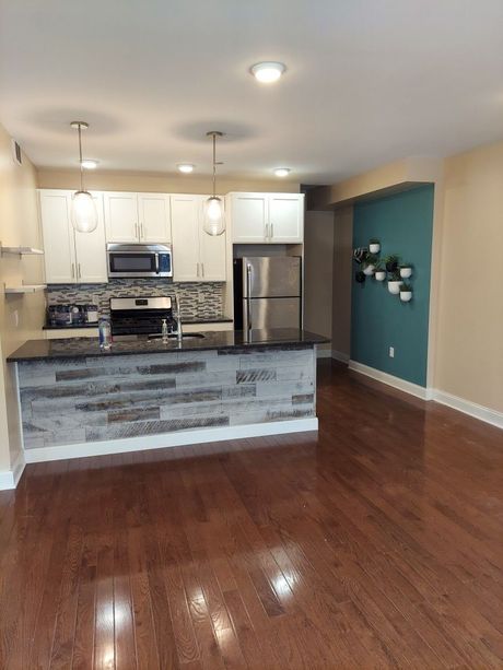 An empty kitchen with hardwood floors and stainless steel appliances