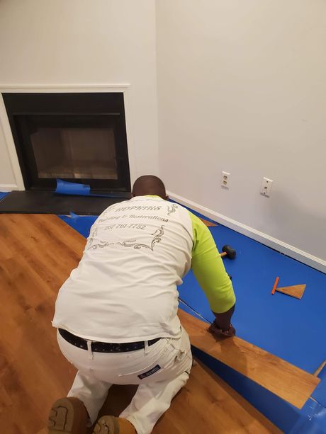A man is kneeling on the floor in front of a fireplace.