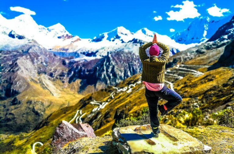 A person is standing in a tree pose on top of a mountain.