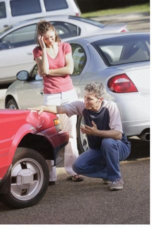 A man and a woman are looking at a damaged car.