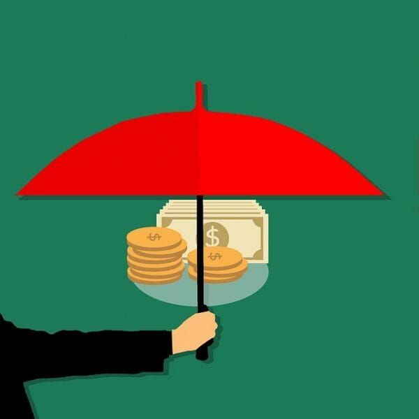 A person is holding an umbrella over a pile of money.