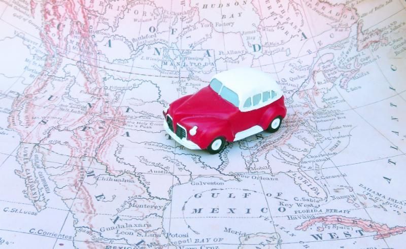 A red toy car is sitting on top of a map