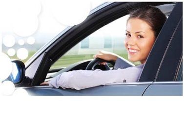 A woman is smiling while sitting in a car.