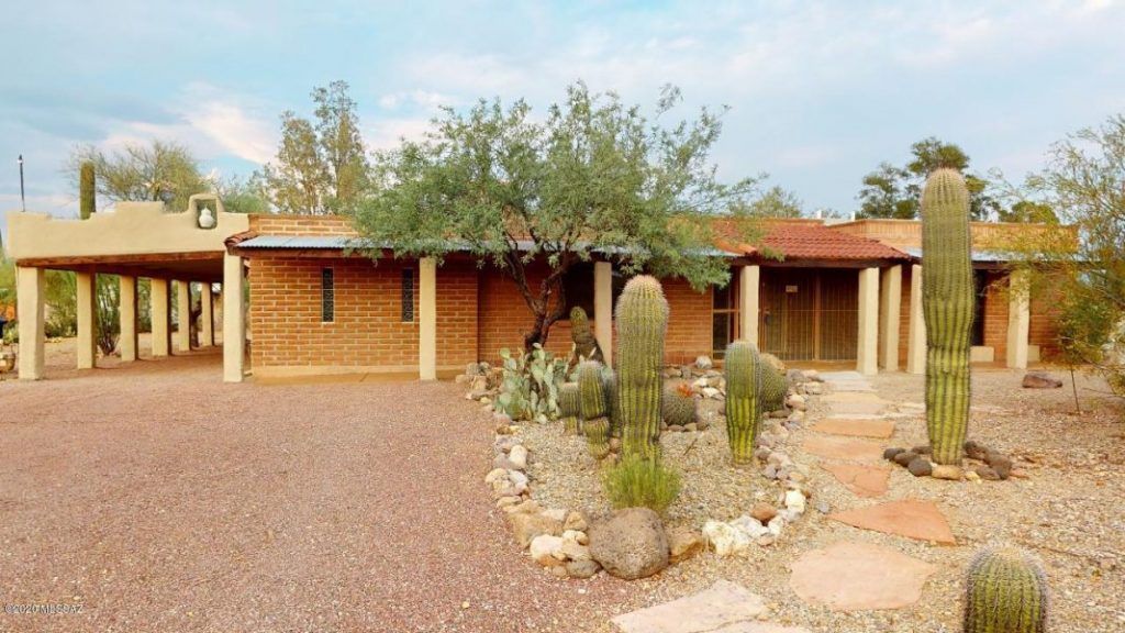 A large brick house with a lot of cactus in front of it.
