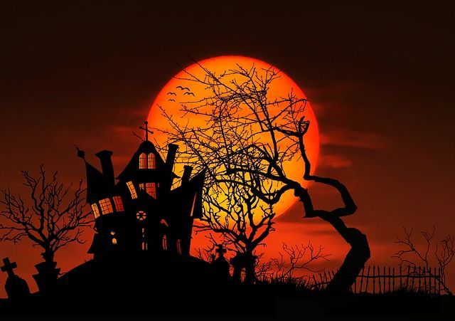 A haunted house is silhouetted against a full moon