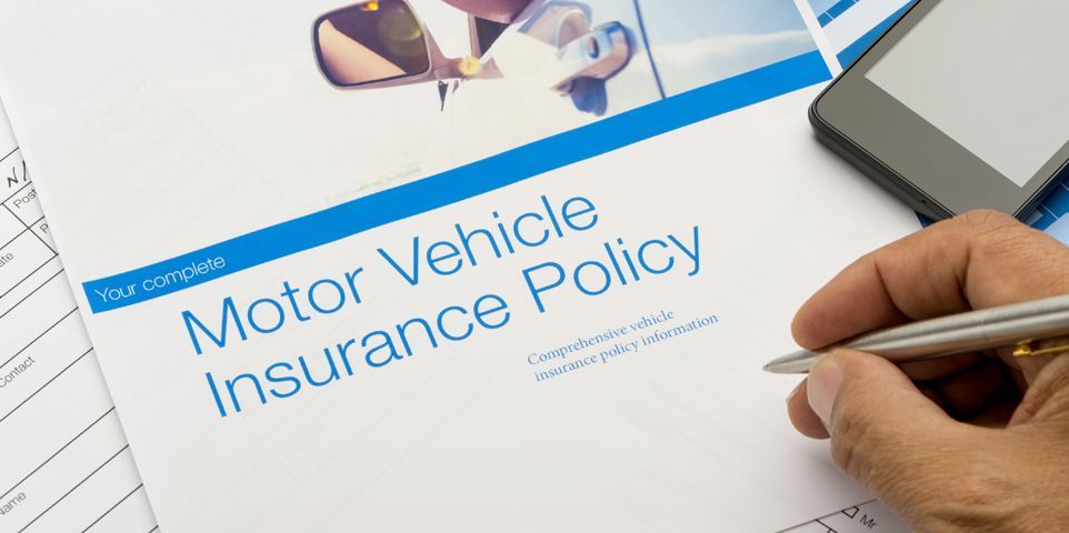 A person is signing a motor vehicle insurance policy.