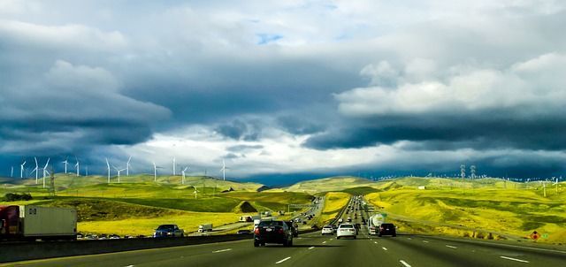 Cars are driving down a highway with wind turbines in the background.