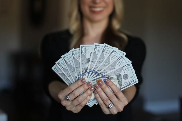 A woman is holding a fan of money in her hands.