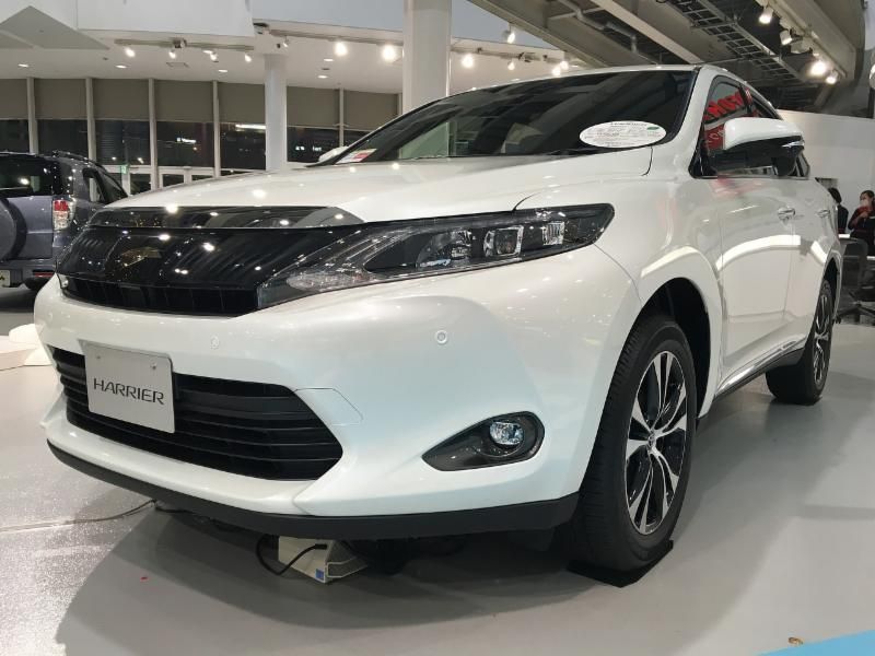 A white toyota harrier is parked in a showroom.