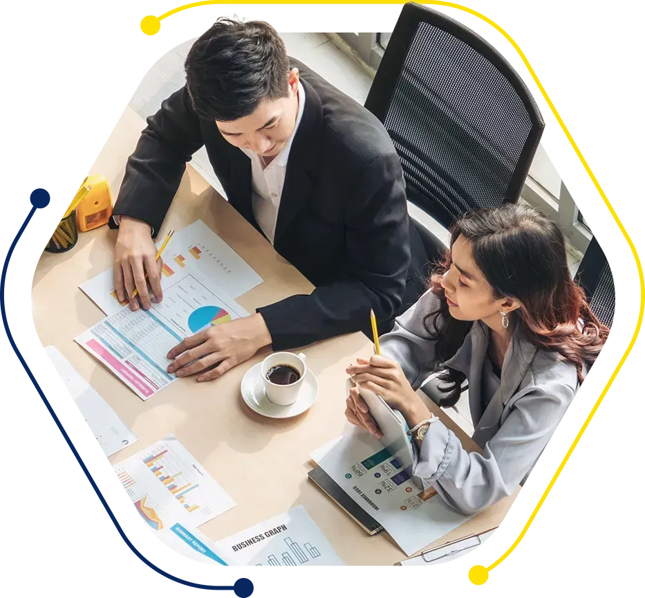 a man and a woman sit at a table looking at business graphs