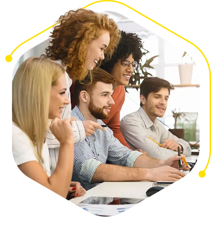 a group of people are sitting around a table looking at a computer screen