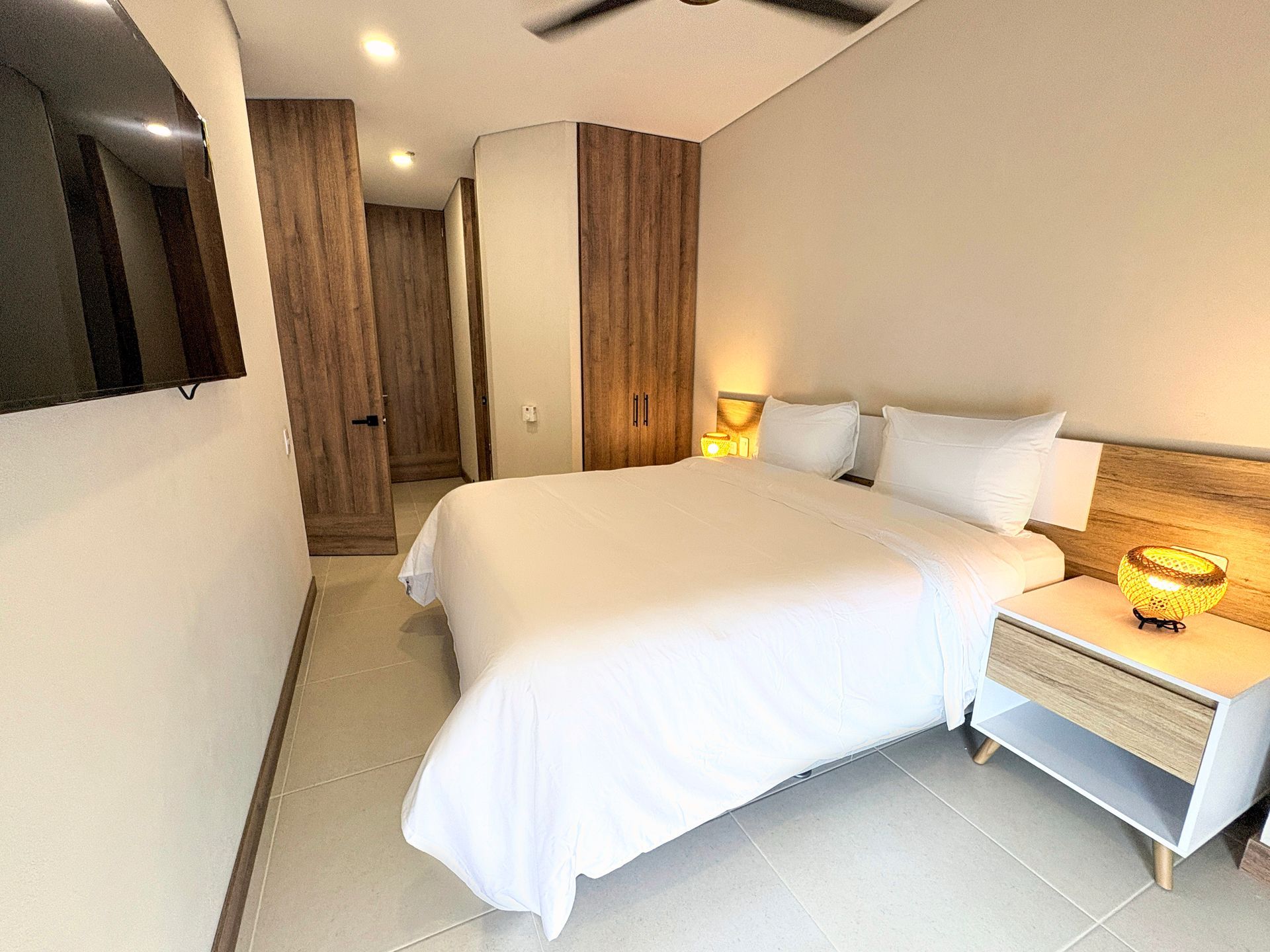 Habitación en hotel Bello Horizonte Santa Marta con cama king, cabecero de madera, sillón y ventanal
