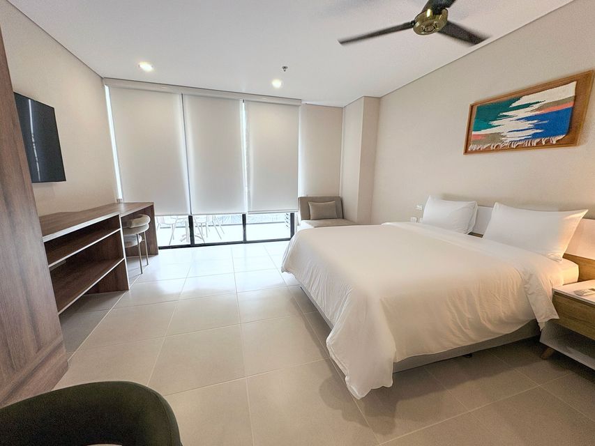 Habitación en hotel Bello Horizonte Santa Marta con cama king, lámparas, ventanal y terraza en Nuruma Suites