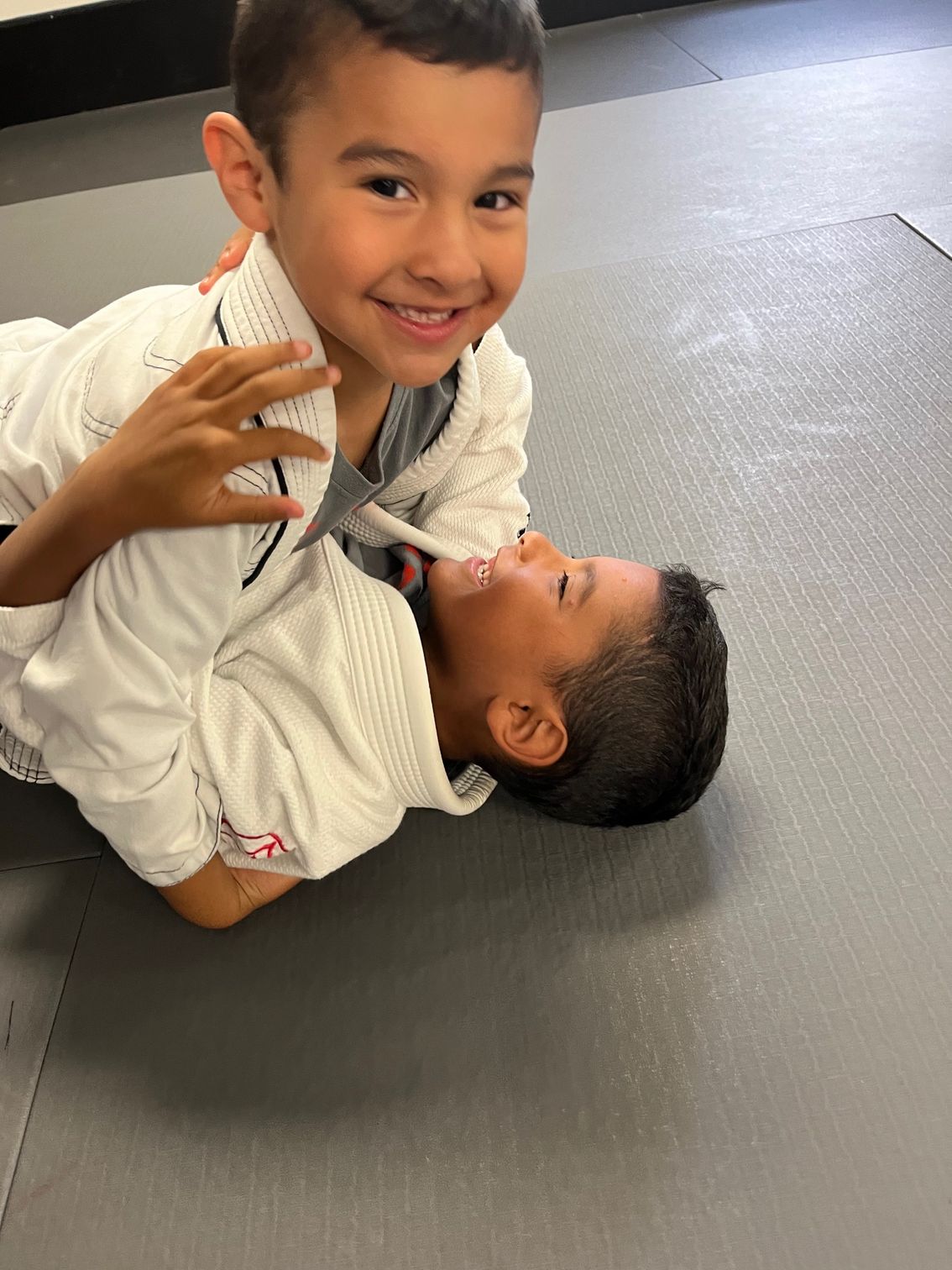 two boys smiling and training grappling together.