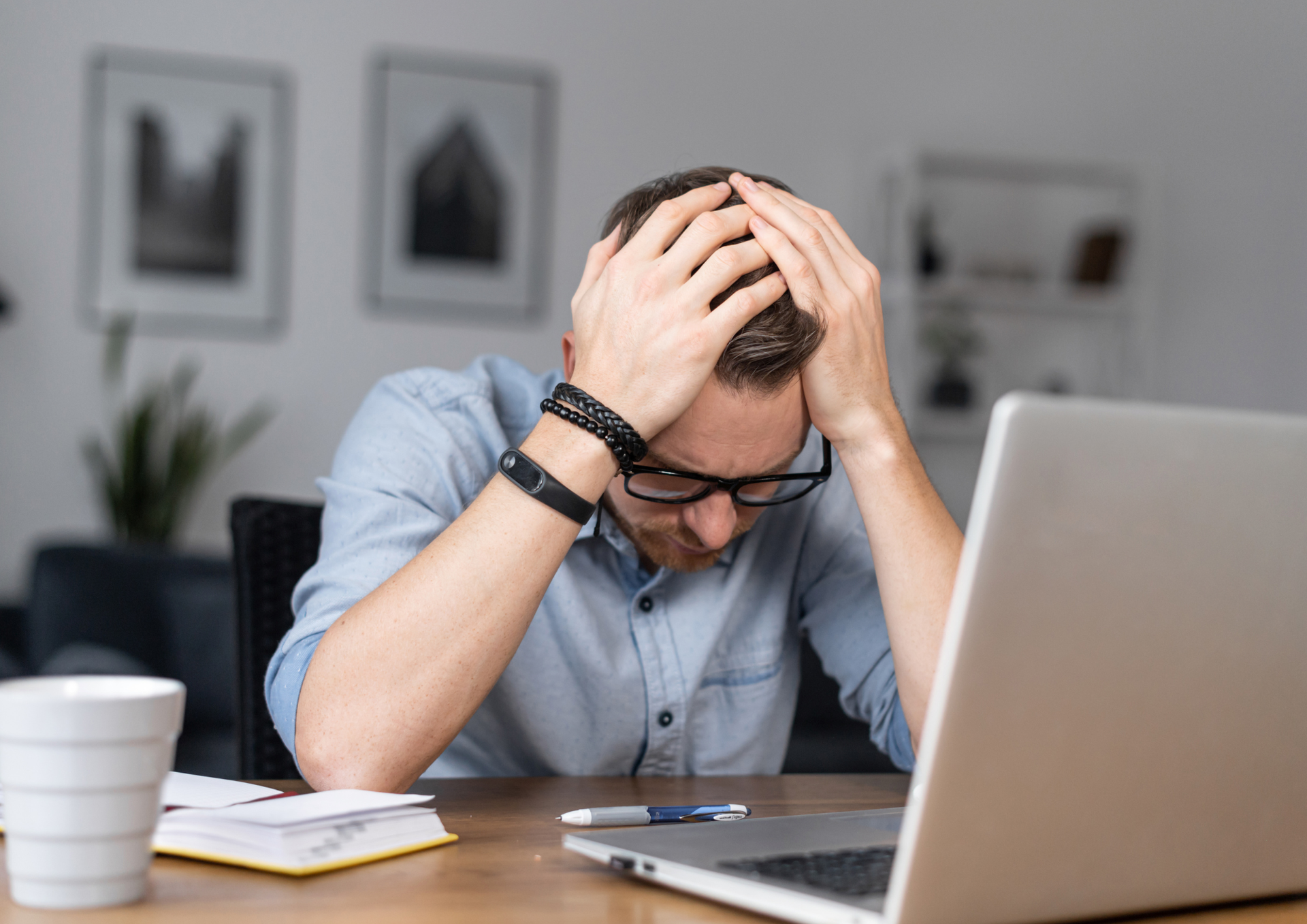 Homme stressé assis à son bureau, les mains sur la tête, regardant son ordinateur portable