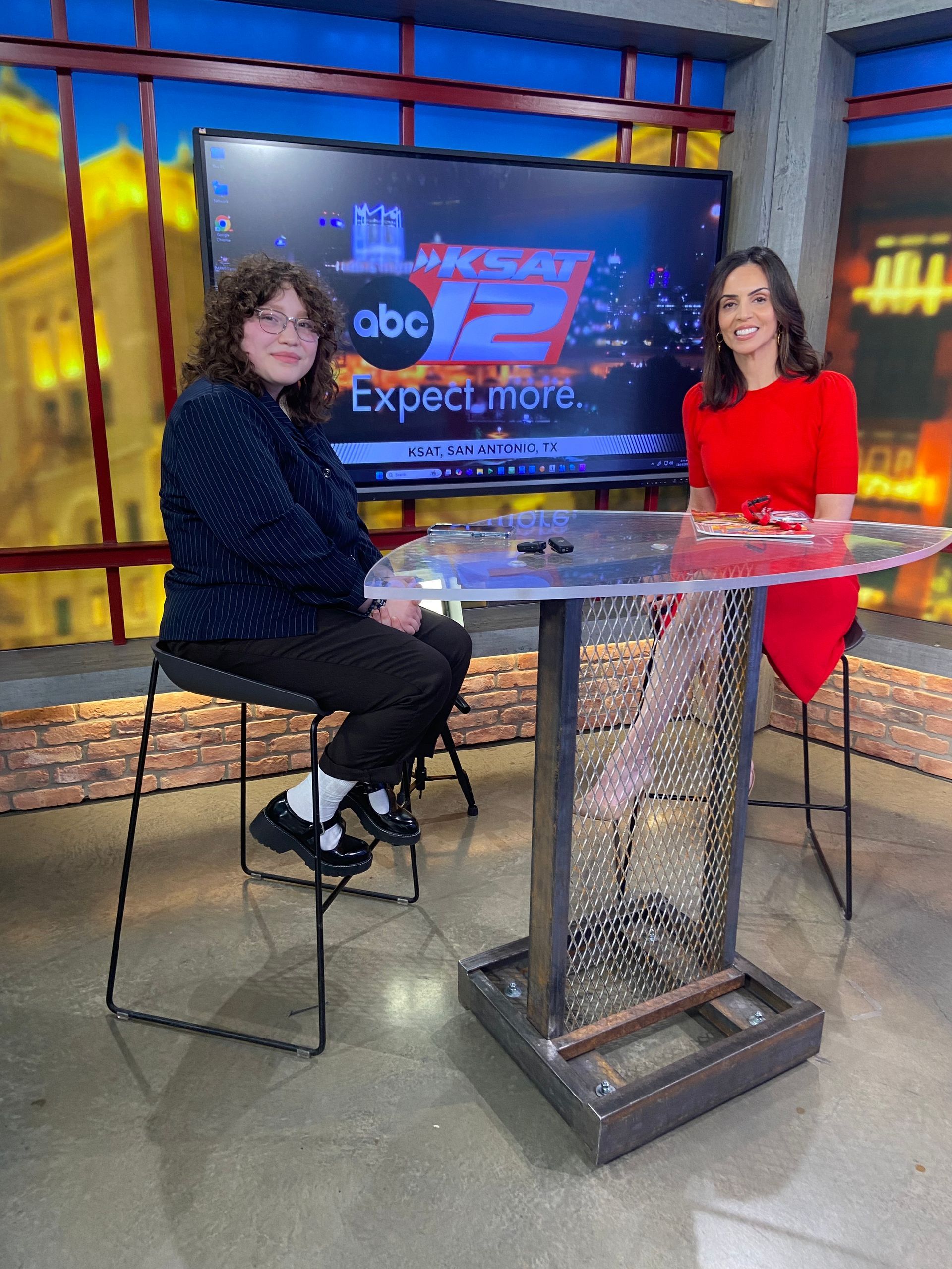 Two people sitting at a tall table in a television news studio with an ABC 12 screen backdrop.