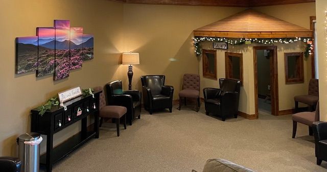 A waiting room with chairs, a console table, wall art, and a small, decorated hut structure for children.