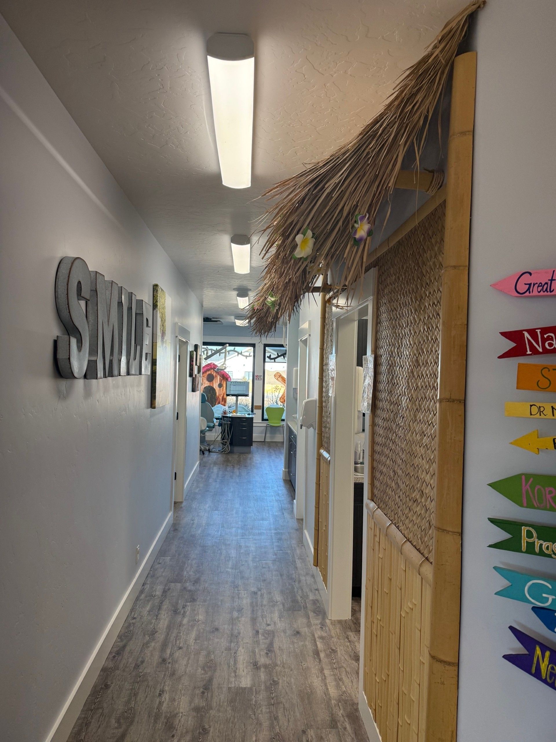 A long office hallway with wood-paneled walls, a straw-thatched awning, metal signage, and colorful directional signs.