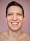 Smiling person against a pink background, bare shoulders visible.