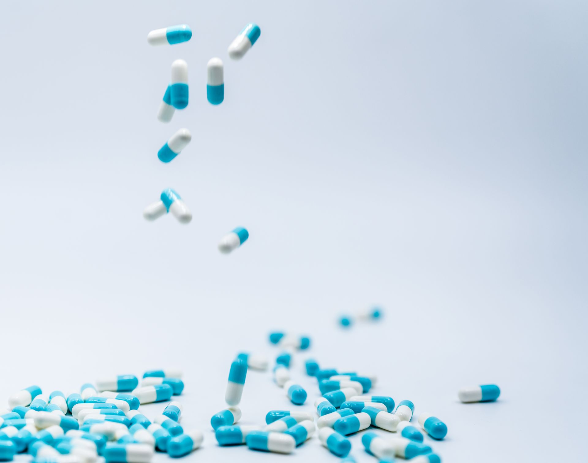 macromed. pharmaceutical compnanies in lebanon. rabih hassouneh. Blue and white pills are falling on a white surface.