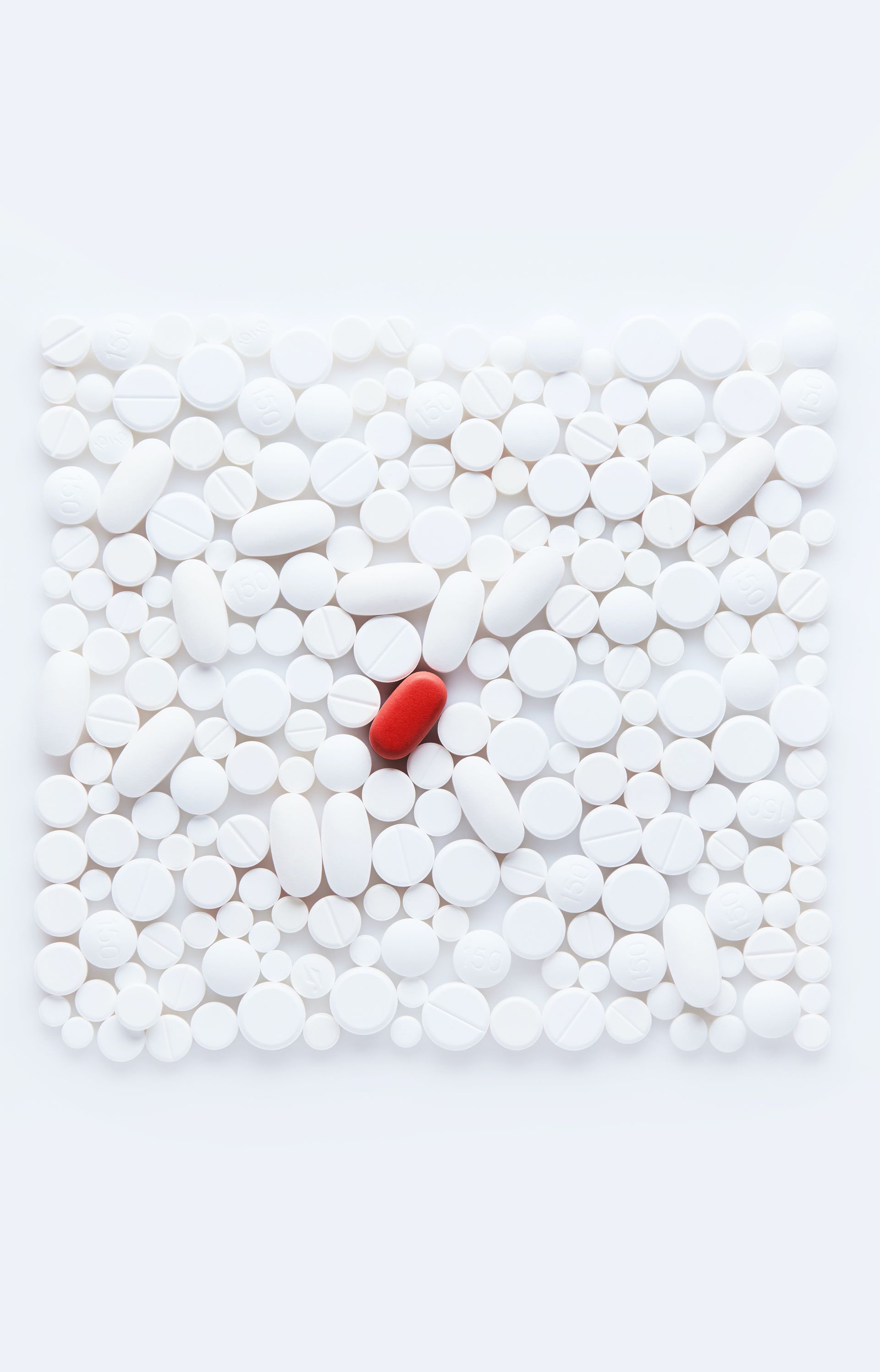 A red heart is in the middle of a pile of white pills