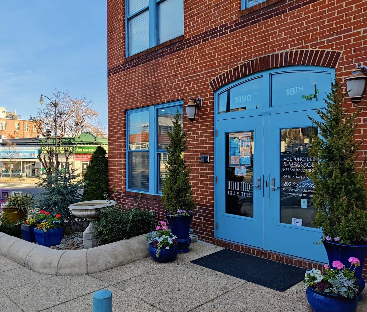 A red brick building with bright blue double doors and window frames.
