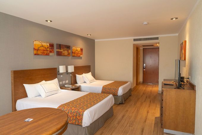 Una habitación de hotel con dos camas tamaño queen, muebles de madera